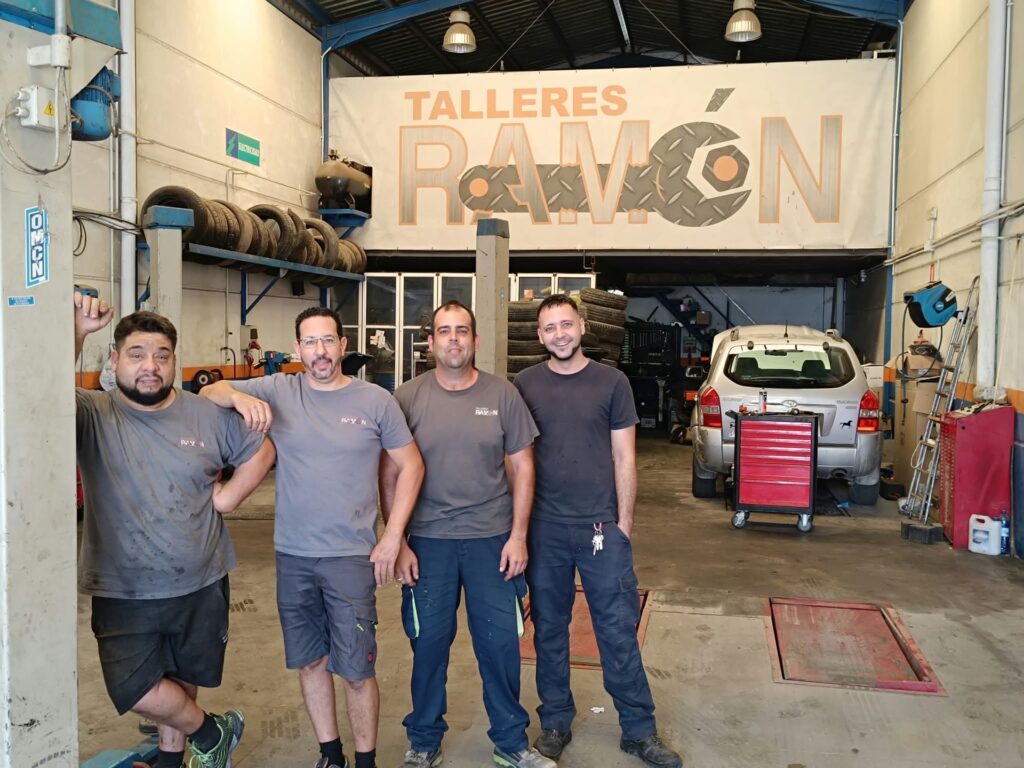 Los cuatro mecánicos de Talleres Ramón delante del rótulo de Los cuatro mecánicos de Talleres Ramón delante del rótulo del taller